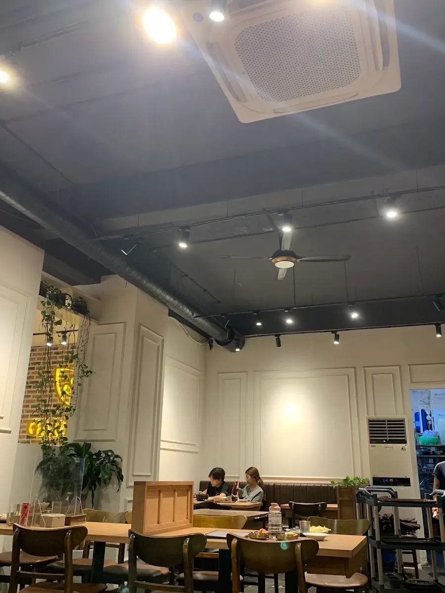 Góc quán Gardenia với đèn vàng, biển neon và cây leo